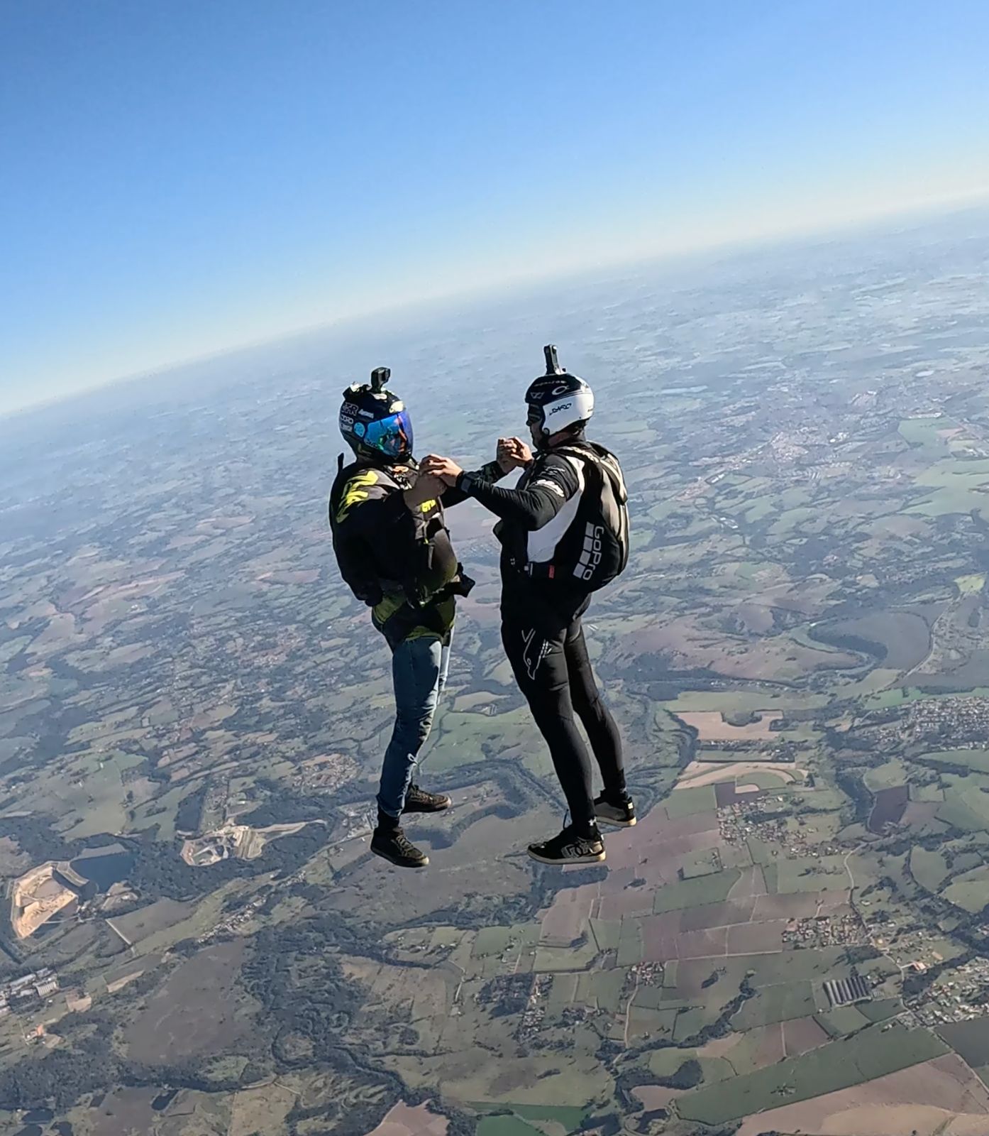 Dois performers de Freefly em queda livre, de mãos dadas, com câmera no capacete